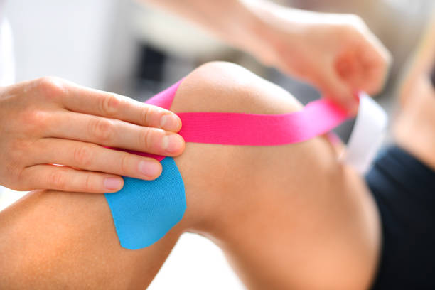 tratamiento de cinta kinesiología con cinta azul y rosa en el brazo lesionado del paciente atleta. - kinesio fotografías e imágenes de stock