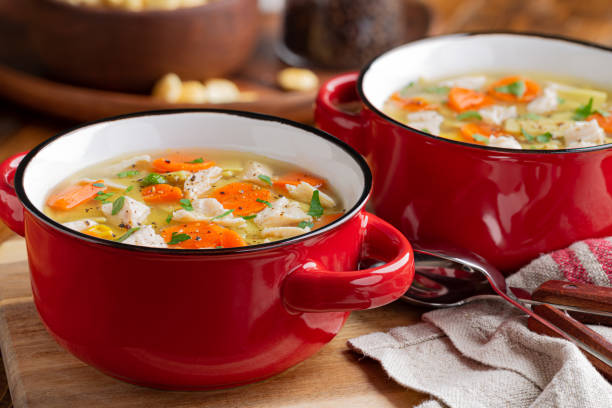 Bowl of Chicken Noodle and Vegetable Soup Closeup of two bowls of chicken noodle and vegetable soup soup on a wooden table chicken soup stock pictures, royalty-free photos & images