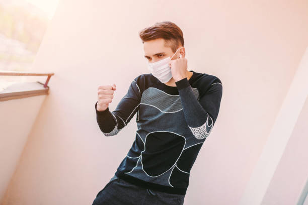 istock Man fighter in protective mask doing boxing exercises on balcony at home 1222571418