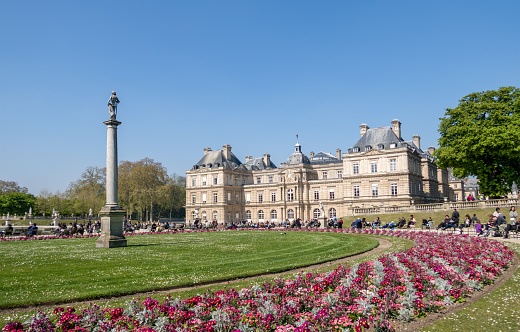 Paris, France - April 11, 2019: People enjoying sunshine in the Luxembourg garden with the Senat in background