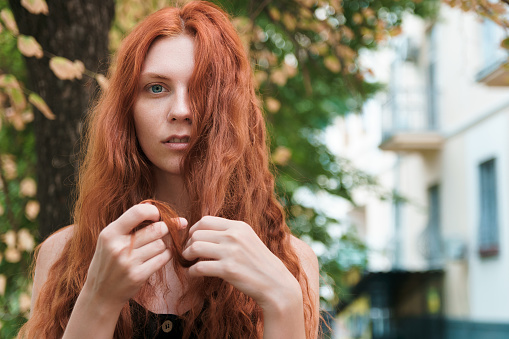 Ginger woman with long hairs in hands. Problem hair concept.