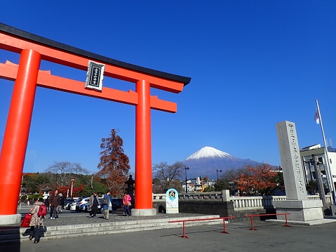 Shizuoka, Japan – December 14 2019: Here is Fuji Sengen Shrine. You can see the bright red torii gate and Mt. Fuji. Mt. Fuji has snow on the summit and it is very beautiful under the blue sky.It is the highest mountain in Japan and an active volcano. Altitude 3776 m . It was registered as a World Heritage Site in 2016.