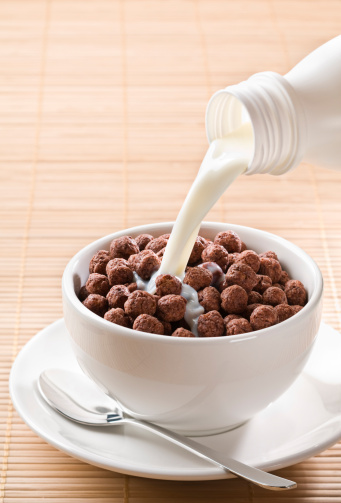Milk pouring on chocolate cereal balls close up