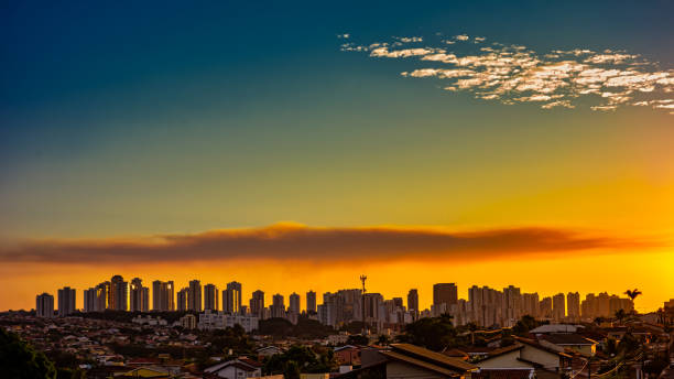 ribeirao preto ville au coucher du soleil - sao paulo, brésil. bâtiments situés sur l’avenue joao fiusa à ribeirao preto à l’horizon au coucher du soleil avec un ciel bleu avec quelques nuages. - sunset vacations orange glowing photos et images de collection