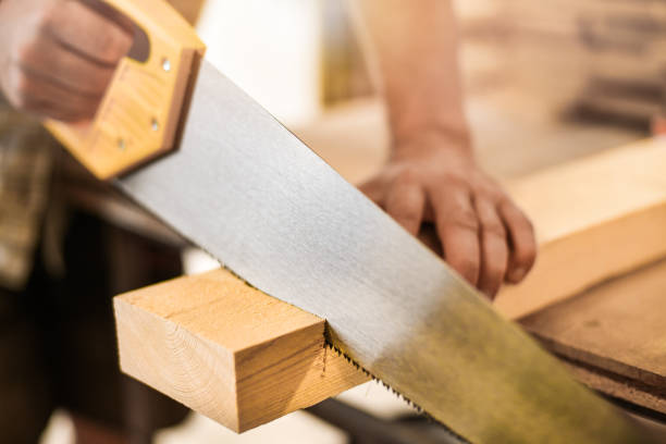 istock Worker hands use a wood cutter or saw on wooden board. 1222581528