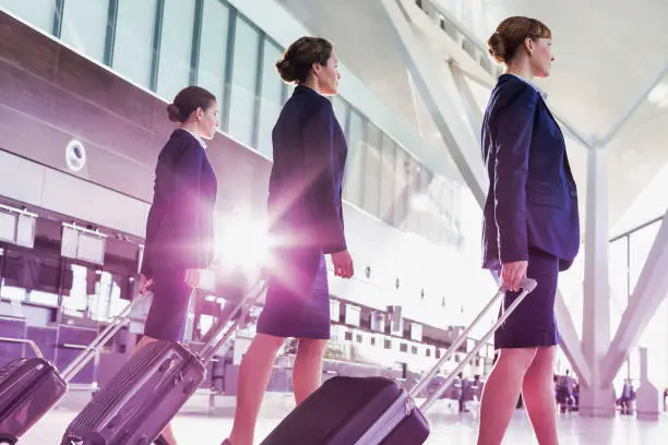 Portrait of young beautiful confident flight attendants walking in airport