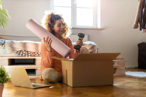 Woman unpacking box with workout equipment at home Woman unpacking box with workout equipment at home net sports equipment stock pictures, royalty-free photos & images