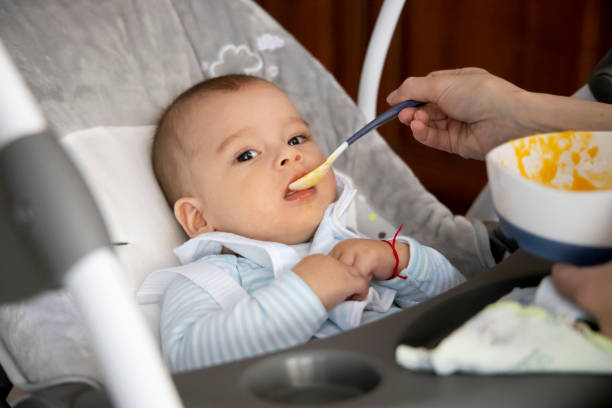 istock First feeding a baby. Feeding pumpkin puree. Happy baby. 1222584792