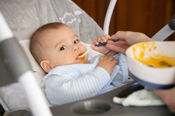 istock First feeding a baby. Feeding pumpkin puree. Happy baby. 1222584801