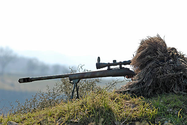 Sniper Soldier Silhouette in Ghillie Suit Aiming with Precision Rifle stock photo