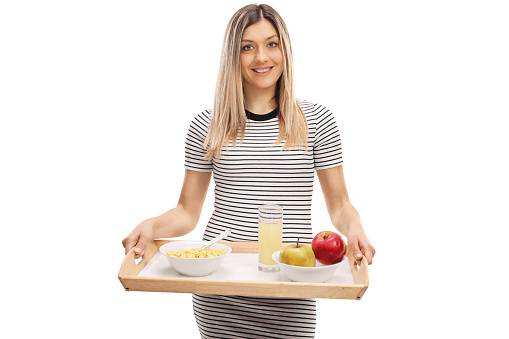 Young casual woman holding a tray with breakfast isolated on white background