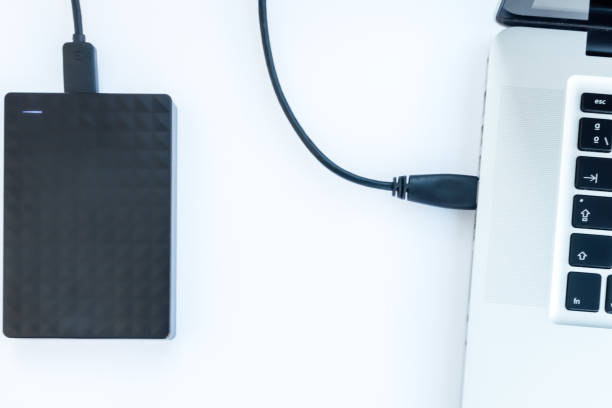 istock black ssd hard drive with cable connected to a laptop with white background 1222587701