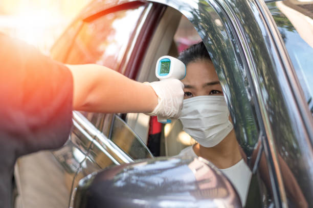 nuevo concepto normal. la mujer asiática conductora con máscara facial que entra en el protector de la puerta utilizan termómetro infrarrojo para medir la fiebre de temperatura que impide el coronavirus covid-19. - 2947 fotografías e imágenes de stock