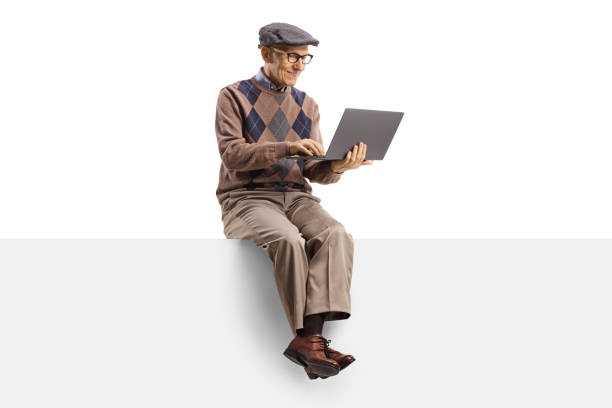 istock Happy elderly man sitting on a blank panel and working on a laptop computer 1222590679