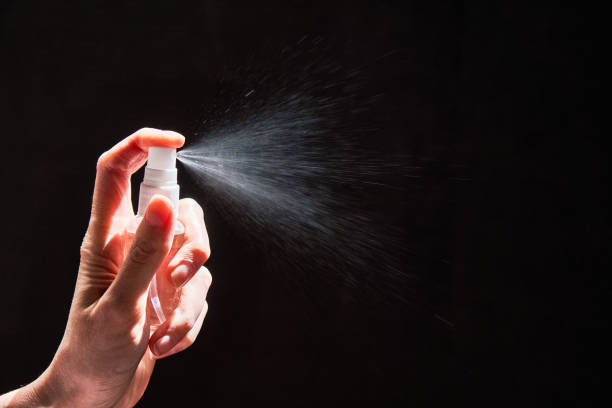 istock Human hand spraying sanitizer over black background 1222591736