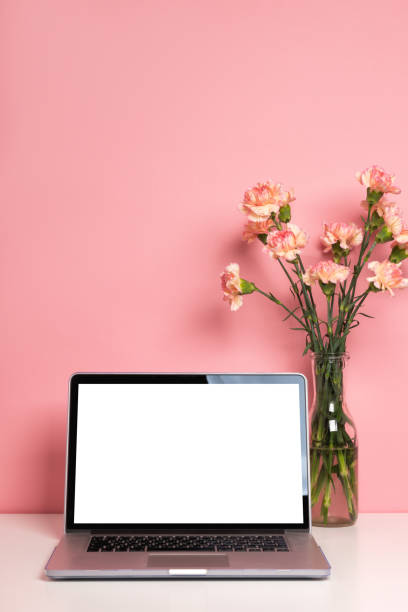 istock Laptop mock up on white table with a beautiful pink carnation flowers 1222591883