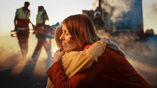 mère blessée et jeune fille se réunissent après terrible accident de la route accident de voiture, ils étreignent heureusement. à l’arrière-plan par la fumée et le feu, les ambulanciers paramédicaux courageux et les pompiers sauvent des vies - rescue worker photos et images de collection