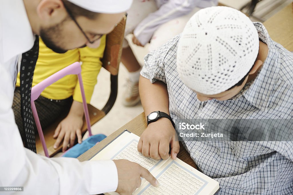 Attività di formazione in aula, musulmana insegnante mostrando Corano per bambino - Foto stock royalty-free di Corano