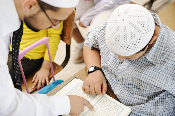 Education activities in classroom, Muslim teacher showing Koran to kid stock photo