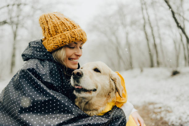 donna sorridente e il suo cane in una giornata innevata - animal dog winter snow foto e immagini stock