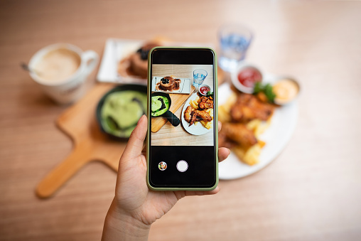 Woman's hand was taking photo of her food with smart phone.