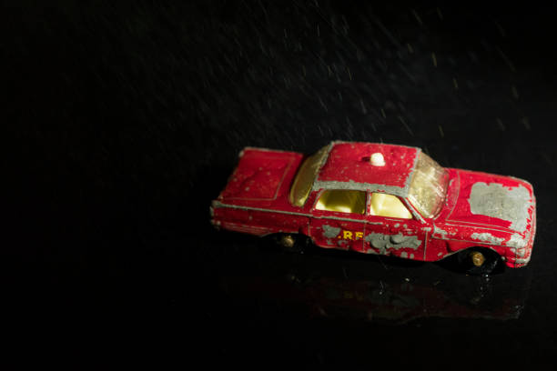 istock Single Red Toy Car on a Black Background with Water Raining Down 1222603590