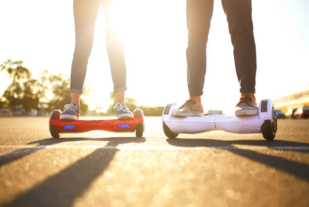 Young man and woman riding on the Hoverboard in the park. Young man and woman riding on the Hoverboard in the park. Close Up of Dual Wheel Self Balancing Electric Skateboard Smart hoverboard stock pictures, royalty-free photos & images
