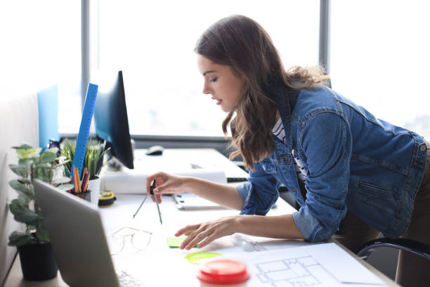 istock Young architect drawing with a compass on blueprint and smiling while working in the creative office. 1222604364