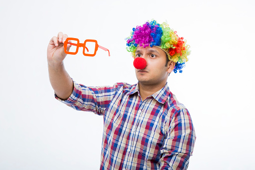 Humor and fun concept. A clown in a bright costume holds a sign for the inscription.