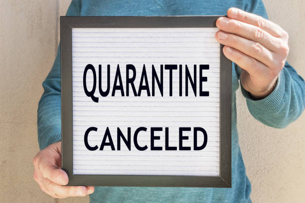 A man holds a placard with the text message QUARANTINE CANCELED . The end of quarantine. Hotel, cafe, local store, service owner meets guests after the coronavirus pandemic and isolation of people un hombre sostiene un cartel con el mensaje de texto quarantine canceled . el fin de la cuarentena. hotel, cafetería, tienda local, propietario del servicio se reúne con los huéspedes después de la pandemia de coronavirus y el aislamiento de las person