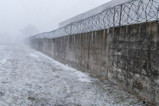 Brick fence with barbed wire on a snowy day