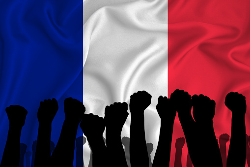Silhouette of raised arms and clenched fists on the background of the flag of France. The concept of power, power, conflict. With place for your text.