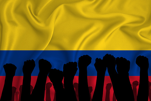 Silhouette of raised arms and clenched fists on the background of the flag of colombia. The concept of power, power, conflict. With place for your text.