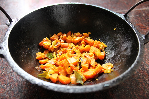 Carrot thoran in a traditional iron pot.