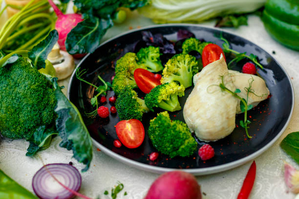 Boiled chicken breast with broccoli and tomatoes on a decorated table