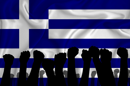 Silhouette of raised arms and clenched fists on the background of the flag of Greece. The concept of power, power, conflict. With place for your text.