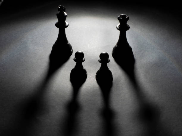 istock Black king and queen chess and two black pawns backlighting 1222614608