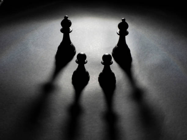 istock Two black bishops and two black pawns backlighting 1222615203