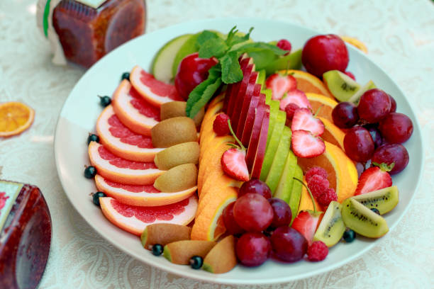 istock a plate of fruit assorted. Kiwi, grapefruit, oranges, apples, grapes and strawberries. On a white plate. Healthy food 1222620557