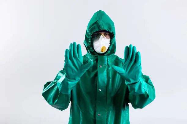 Person wearing a hazmat suit showing his hands in gloves stock photo