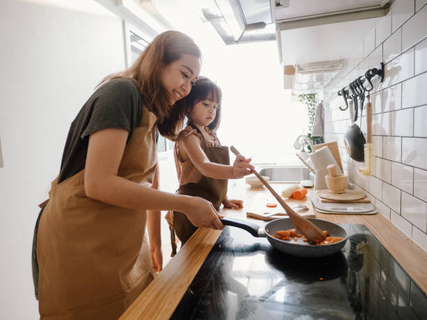 istock Millennial mother preparing breakfast at kitchen with her daugther's helping hand cooking omelet at home. 1222623095