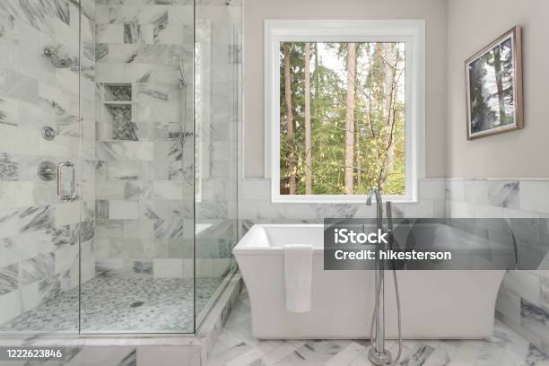 Master Bathroom Interior In Luxury Home With Large Shower With Elegant Tile And Soaking Bathtub Includes Large Window With View Of Trees Stock Photo - Download Image Now