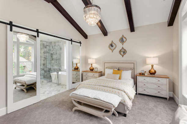 Master bedroom in new luxury home with chandelier and view of bathroom Master bedroom in luxury home bedroom stock pictures, royalty-free photos & images