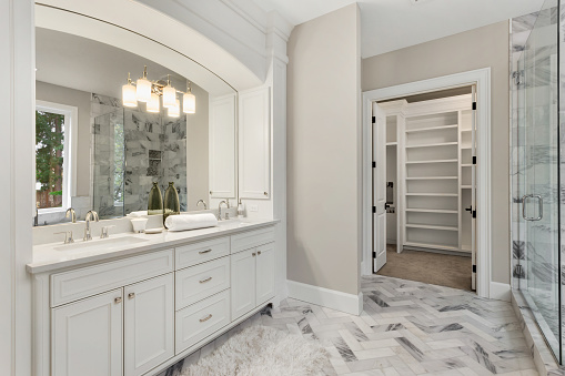 Hermoso interior de baño en nueva casa de lujo con tocador, espejo y gabinetes photo