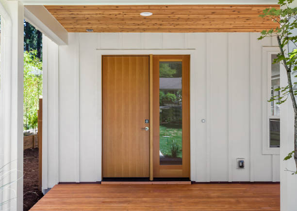 Covered porch and front door of beautiful new home. Features white siding and rich warm wood porch and ceiling. Door is closed. Facade of home with covered porch and door wooden porch stock pictures, royalty-free photos & images