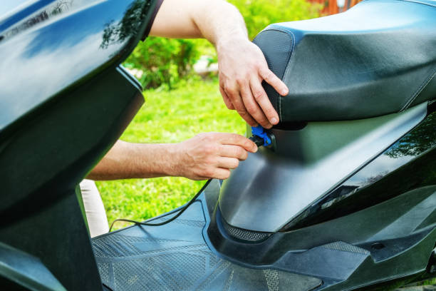 istock Man's hand inserts plug into charging socket of electric scooter. 1222624908