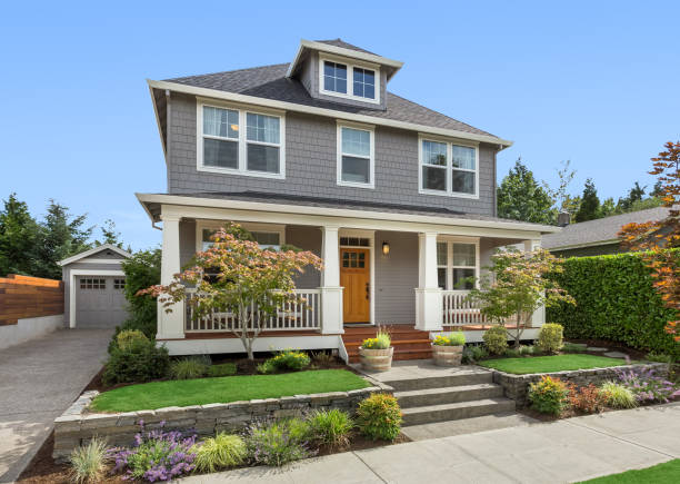 Beautiful craftsman home exterior on bright sunny day with green grass and blue sky facade of home with manicured lawn, and backdrop of trees and blue sky outdoors stock pictures, royalty-free photos & images