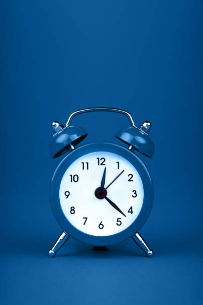 istock Close up one classic alarm clock over blue background 1222625314