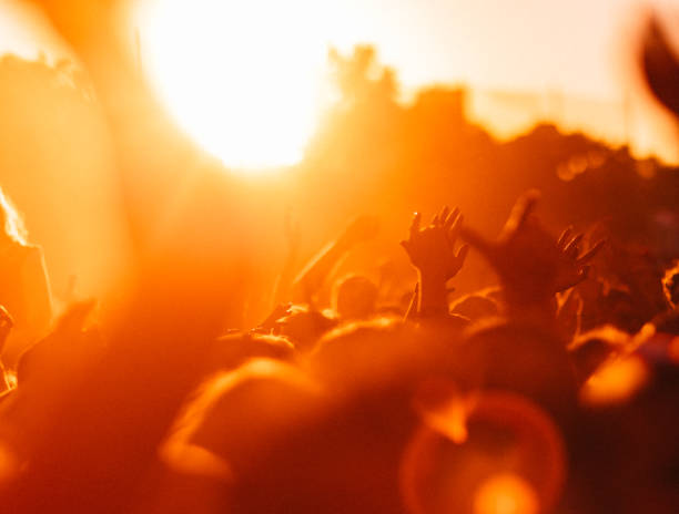 Multitud de gente animando en un festival de música al atardecer - foto de stock