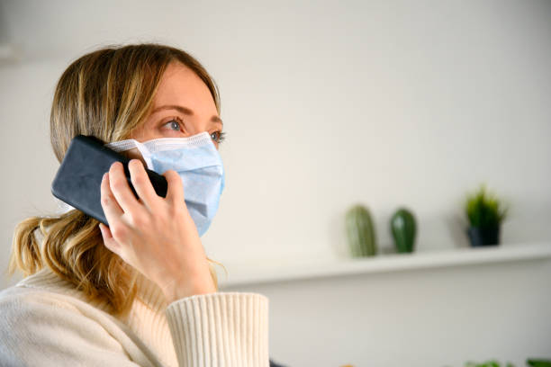 istock Woman wearing protective mask phoning from home 1222631068